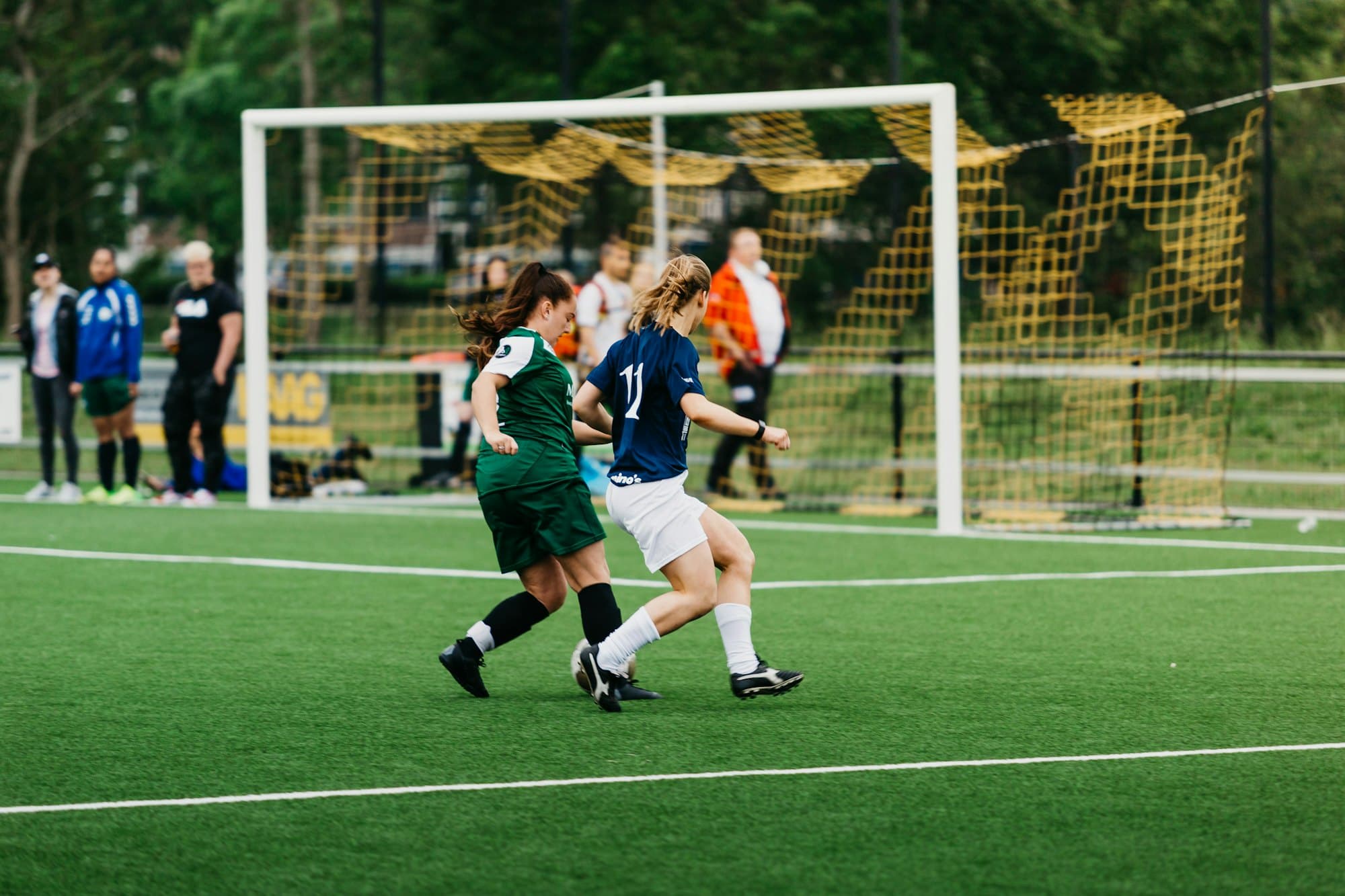 Duel au ballon entre deux joueuses sur un terrain de football synthétique