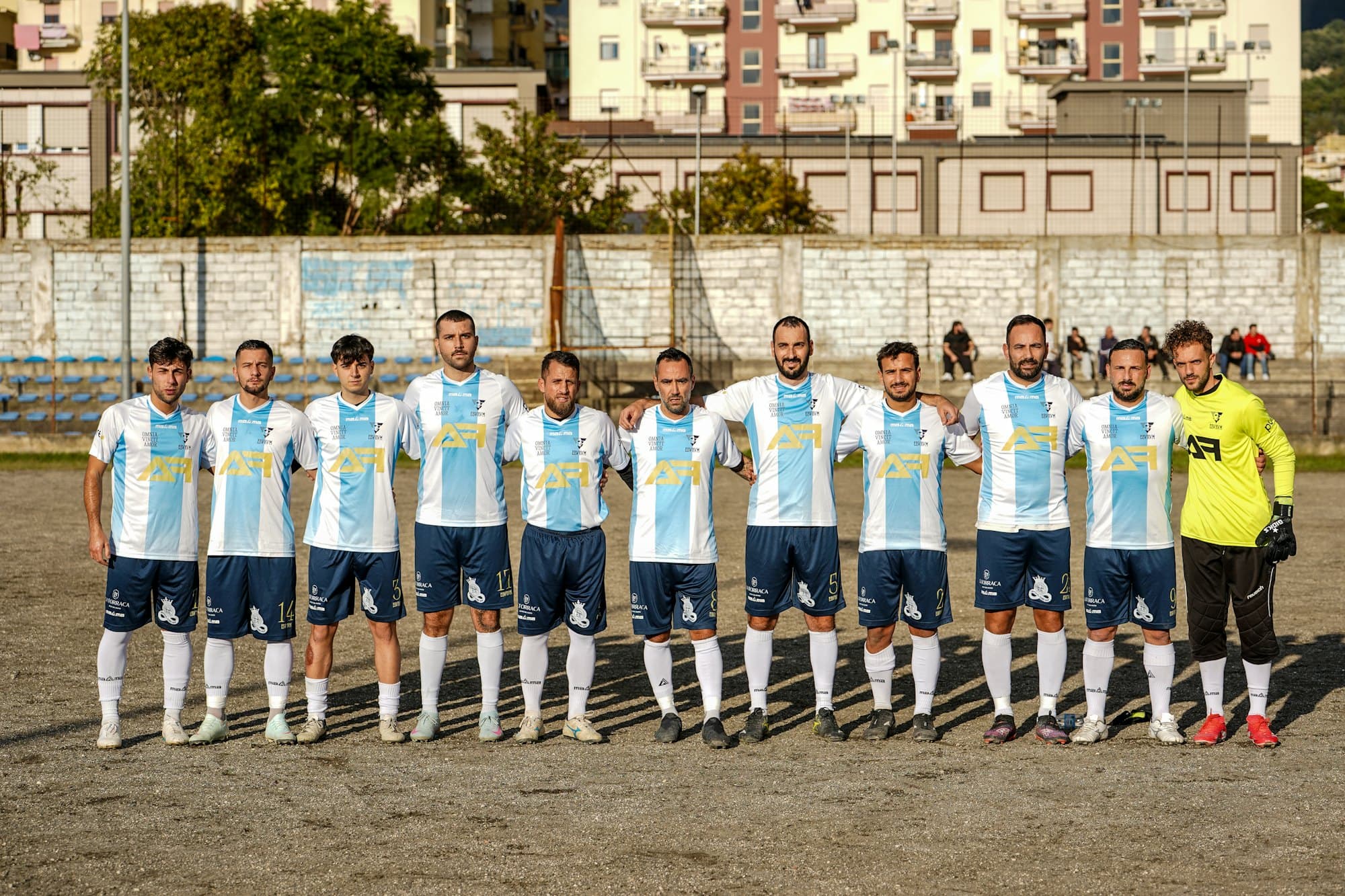 Équipe de football alignée sur le terrain avant le match, maillots blanc et bleu ciel